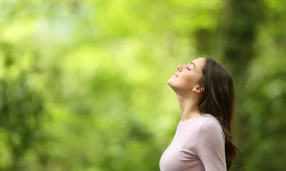 mujer-relajada-respirando-aire-fresco-en-un-bosque-verde